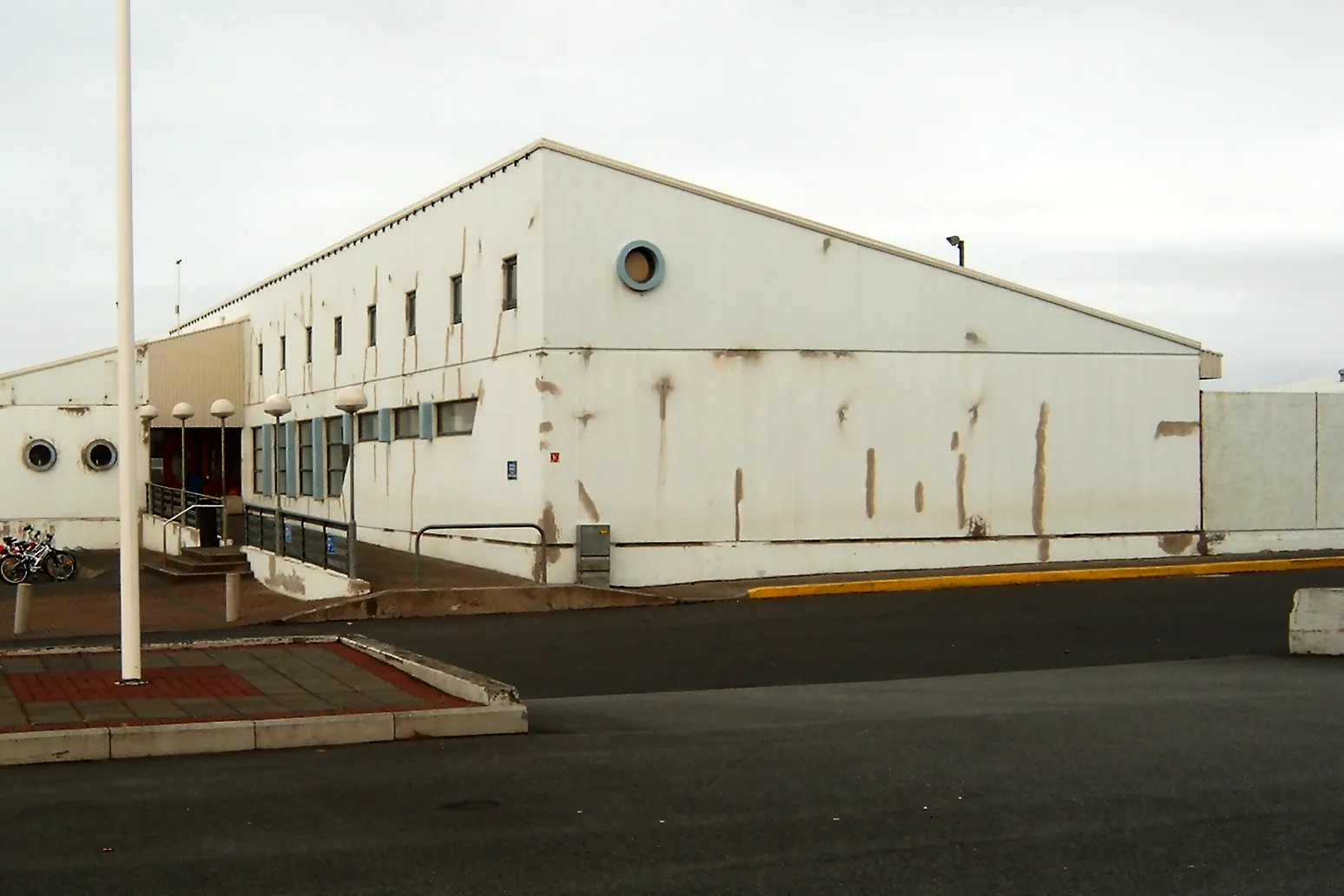 Veðraðir hvítir útveggir Sundmiðstöðvarinnar í Reykjanesbæ